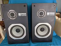 Pair of Yamaha NS 220 RM speakers front view showing the woofer, tweeter, and Yamaha Rock Monitor logos.