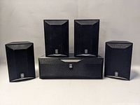 Front view of all five Yamaha speakers showing one center channel speaker and four satellite speakers arranged around it.