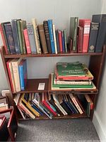 Three shelves filled with various books of different sizes and genres, showing spines and titles.