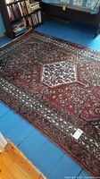 Full view of red patterned rug laid on painted wood floor