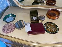 Overview photo of all home decor items arranged on a dresser including ashtrays, compact mirror, heart-shaped trinket box, maroon box, and decorative plate.