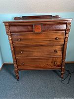 Front view of the solid mahogany dresser showing four drawers, carved details, and wooden knobs on each drawer.