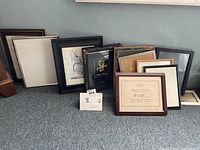 Collection of mostly 8x10 picture frames arranged on floor, various styles and colors