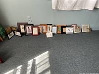 Overview of all 13 4x6 picture frames arranged on floor showing variety of styles and colors, some folding and single frames.