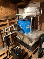 Photo showing a stack of health aids including a bathtub transfer bench, bed bars, and other items in a storage area.