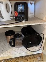 Shelf with white Traditions electric kettle, black two-slice toaster, and white can opener