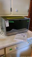 Panasonic microwave on countertop with operating manual placed in front.