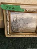 Close-up photo of the smaller painting with 7x6 inch size marked on green tape, showing ornate frame and detailed portion of the artwork depicting bare trees and a cloudy sky with birds.