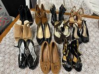 Overview of the 11 pairs of women's shoes showing variety in color and style on a lace-patterned cloth