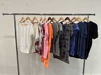 Front view of 10 assorted colored t-shirts hanging on a clothing rack, showing a range of solid colors and patterned designs.