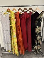 Photo showing a rack with seven dresses in various colors and styles hung on hangers.