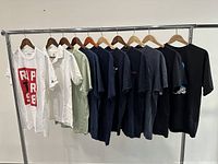 Front view of ten men's t-shirts in various colors and prints hanging on a rack showing front designs and logos.