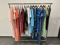 Full rack view showing 14 assorted dresses in various colors including peach, red, black, white, blue, and green.