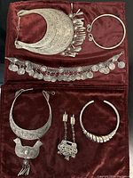 Full set of six vintage silver tone ethnic jewelry items displayed on burgundy velvet background, showing necklaces, bracelets, and earrings with detailed engraving and coin decorations.