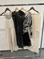 Four unique dresses hanging on a clothing rack showing the full variety of designs and colors.