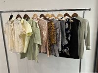 Full view of all tops and jacket on hangers showing variety of colors and styles