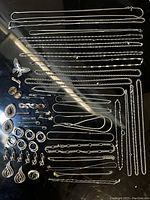 Wide assortment of chain necklaces, earrings, and rings laid out on black surface.