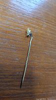 Stick pin with gold nugget laid flat on wood surface showing full length and detail of nugget