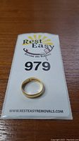 Ring atop auction lot card #979 on wood surface
