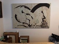 Full view of large abstract painting with black curved shapes on white textured background hung on wall above smaller framed artworks.