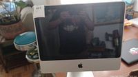 Front view of Apple iMac 20-inch all-in-one computer on desk showing screen and stand.