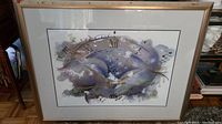 View of framed wall art showing abstract clock in mixed media style with varying shades of blue and neutral tones.