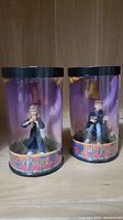 Two Harry Potter mini figurines of Hermione Granger and Ron Weasley in cylindrical packaging with purple background