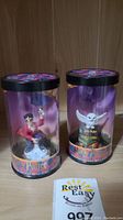 Two cylindrical plastic cases containing Harry Potter and Hedwig mini figurines with themed bases and story scopes, new in packaging.
