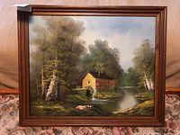 Full frontal view of the framed painting showing water mill, river and trees.