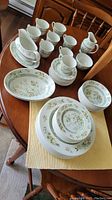 Full overview of the dinnerware set including plates, cups, saucers, creamers, and platters arranged on a wooden table.