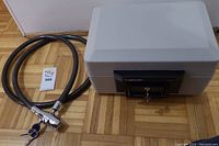 Photo showing light grey Sentry fire safe model 1150 with keys in lock, and cable bike lock coiled beside it with keys visible.