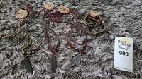 Three Wild Tribe necklaces with feather pendants displayed on carpet, tags attached indicating brand new condition.