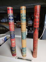 Front view of three cylindrical vintage fire extinguishers showing labels and condition.