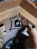 Close-up showing the opened small door with a painted bird figure inside the clock.