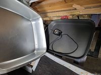 Electric griddle removed from its base showing the black non-stick cooking surface with temperature control dial and cord attached.