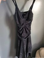 Front view of the black sleeveless ruched evening dress showing ruched detailing and floral pattern.