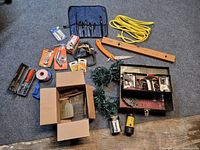 Photo showing a variety of hand tools, hardware, and accessories spread on a carpeted floor.
