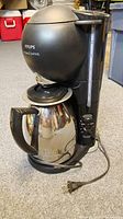 Full view of Krups coffee maker showing spherical top, control buttons, water level indicator, and stainless steel carafe with black handle.
