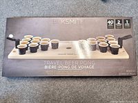 Photo of the Blacksmith travel beer pong game set in its box showing the cups, catapults, and ball on a wooden board layout.