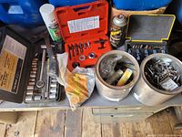 Full view of assorted tools and hardware including socket set, drill bits, hardware containers, spray cans, hammer, and hand tools.