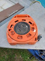Top view of orange roll-up extension cord reel showing four power outlets and handle.
