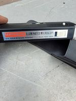 Close-up photo of the brand and specifications label on the microscope body showing 'Leitz Wetzlar Illuminated Microscope' and zoom range of 60x-190x.