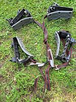 Four Yakima kayak carrier cradles with attached red and black straps placed on grass.