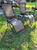 Two chairs side by side on grass, both in upright positions