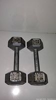 Pair of cast iron hex dumbbells with visible '12' weight markings showing front and top down view, illustrating condition including surface rust and paint wear.