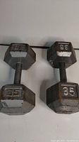 Overhead view of two 35 lb hexagon dumbbells on white surface
