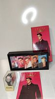 Photo showing the collectible stamp watch in original plastic packaging, five Elvis Presley cassette tapes in a black display case, and the Elvis Presley book with red cover.