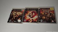 Three PS3 video game cases: Golden Axe Beast Rider, Heavenly Sword, and Overlord Raising Hell on a white background
