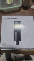 Photo of the unopened Audio Technica AT2020 microphone box on a surface, showing product image and brand labeling.