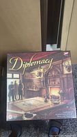 Front of Diplomacy board game box showing artwork with map and people in a historic room.